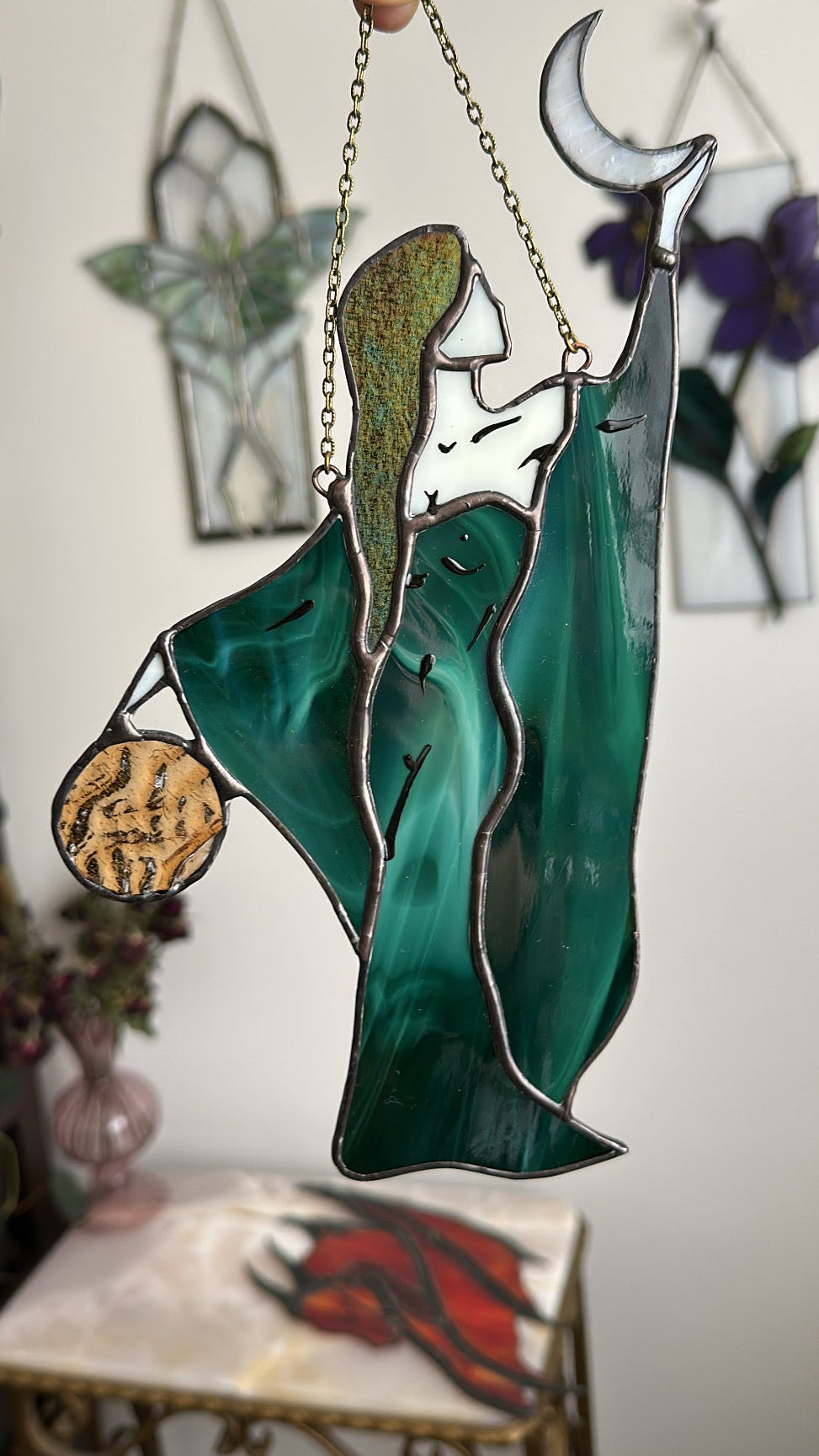 Stained glass suncatcher of a woman with a moon and a crescent, hanging from a chain.