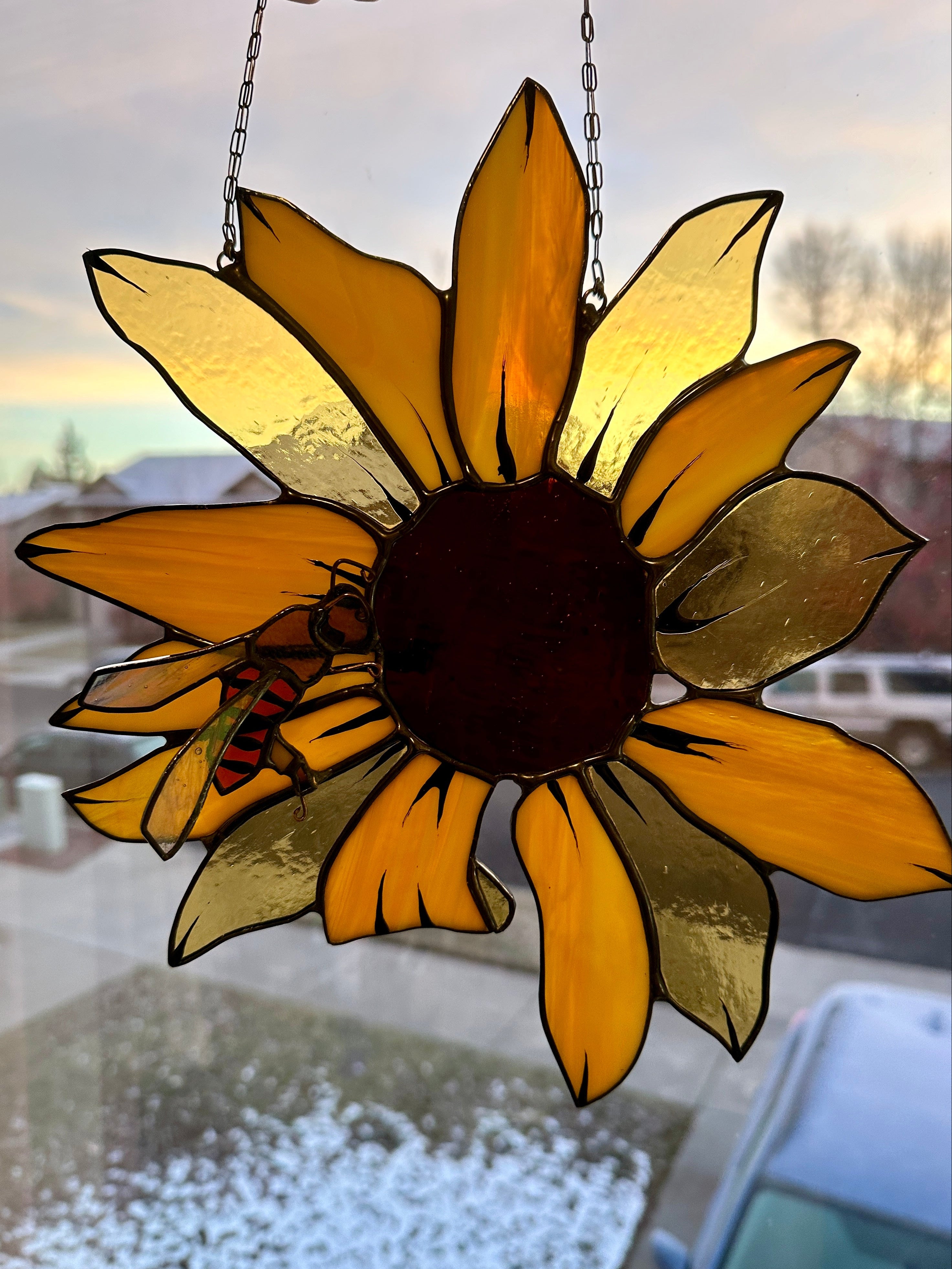 Stained glass sunflower hanging by a chain indoors.